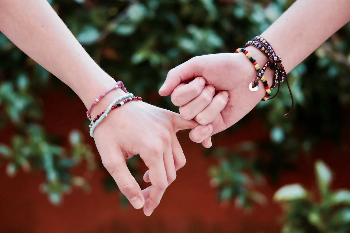 two lovers holding hands wearing diy bracelets made with beads and string