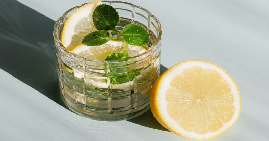 glass full of water with slices of orange in it to meet daily water goals